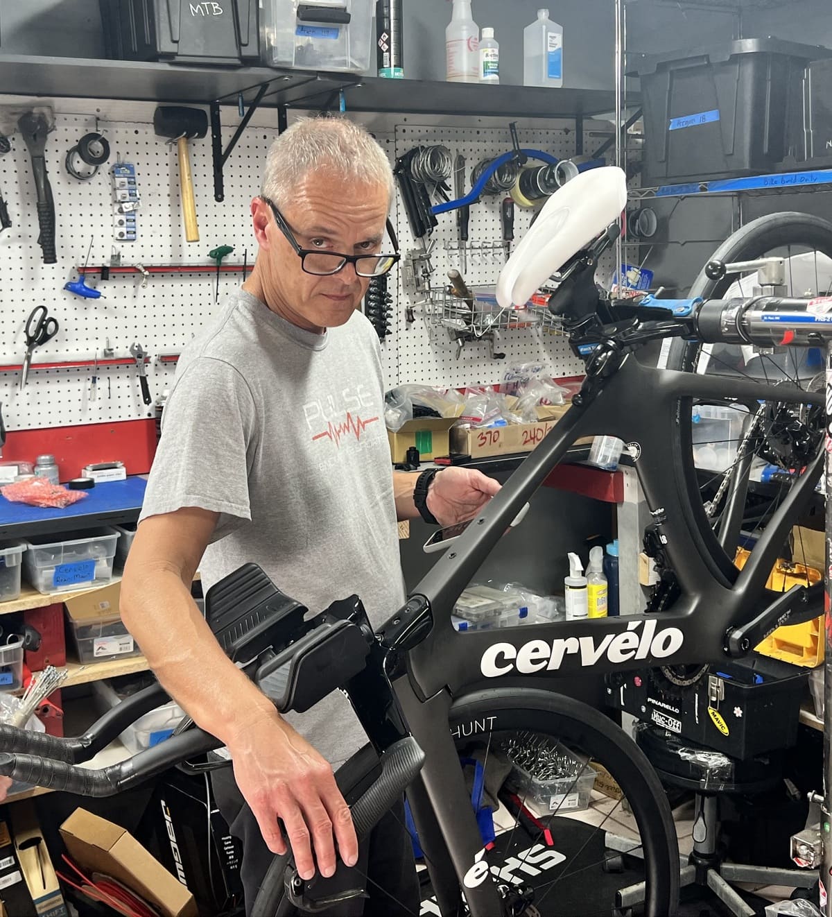 Man working on a Cervélo bicycle in a workshop.