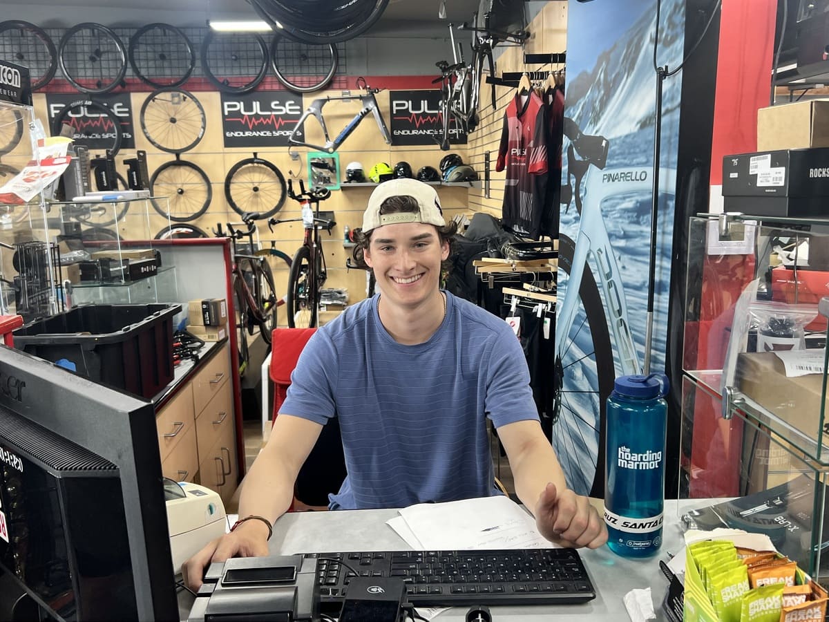 Person sitting at a desk in a bike shop with computers and products around